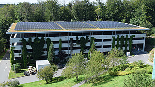 Ein Gebäude im Grünen mit Solopanelen auf einem begrünten Dach