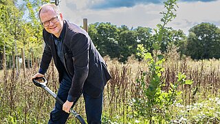 Bundesumweltminister Schneider mit Spaten in der Hand beim Baumpflanzen
