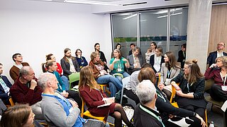 Gruppe von Menschen sitzt in einem Raum bei einer Diskussionsrunde, einige mit Namensschildern, ANK Fachforum 2025.