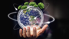 Hand hält eine digitale Erdkugel mit Bäumen auf der Oberfläche und leuchtenden Umlaufbahnen vor dunklem Hintergrund
