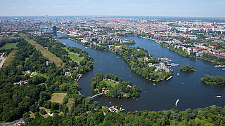 Luftaufnahme der Rummelsburger Bucht mit Wasserflächen, grünen Uferbereichen und städtischer Bebauung im Hintergrund