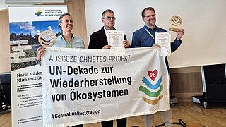 Projektmitarbeitende halten bei der Preisverleihung ein Banner 